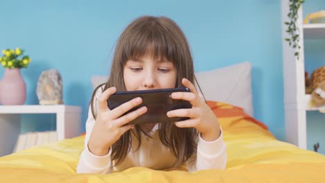 Cute-little-girl-playing-on-the-phone-is-happy,-winning.